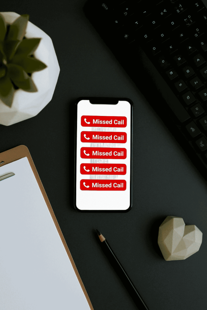 A smartphone screen displaying multiple missed call notifications on an office desk, illustrating lost business leads.